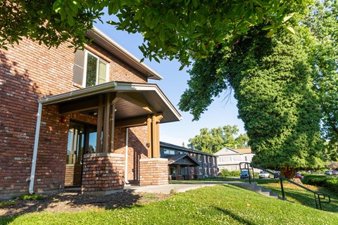 the side of a brick house with a yard and a tree