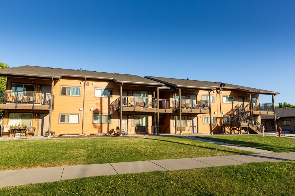 an apartment building with balconies and a grass yard