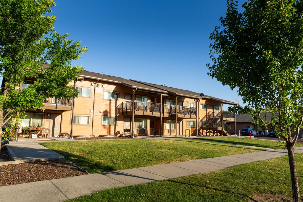 an apartment building with a sidewalk and a lawn