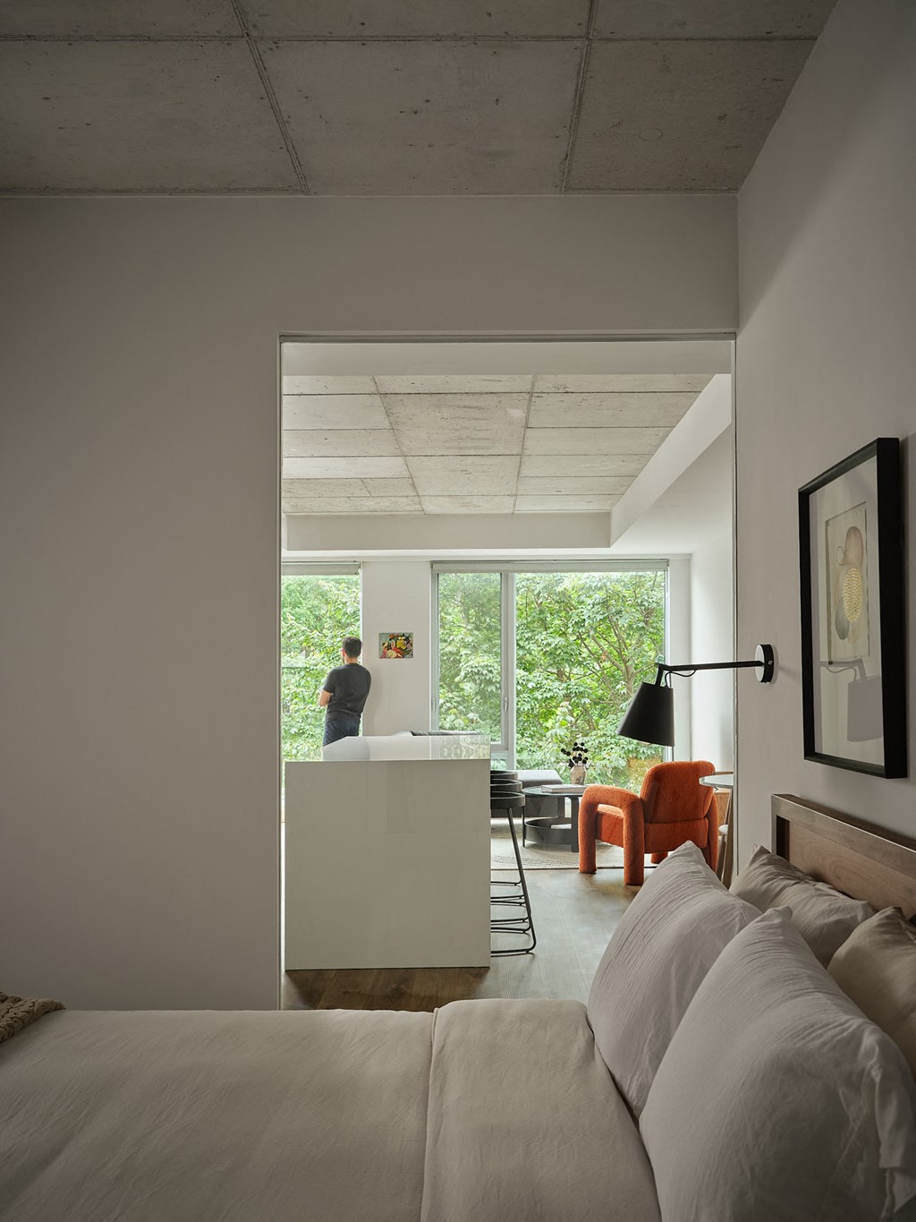 a bedroom with a bed and a view of a kitchen and a living room