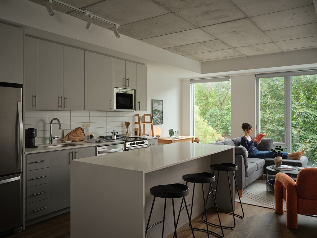 a kitchen and living room with a person sitting on a couch