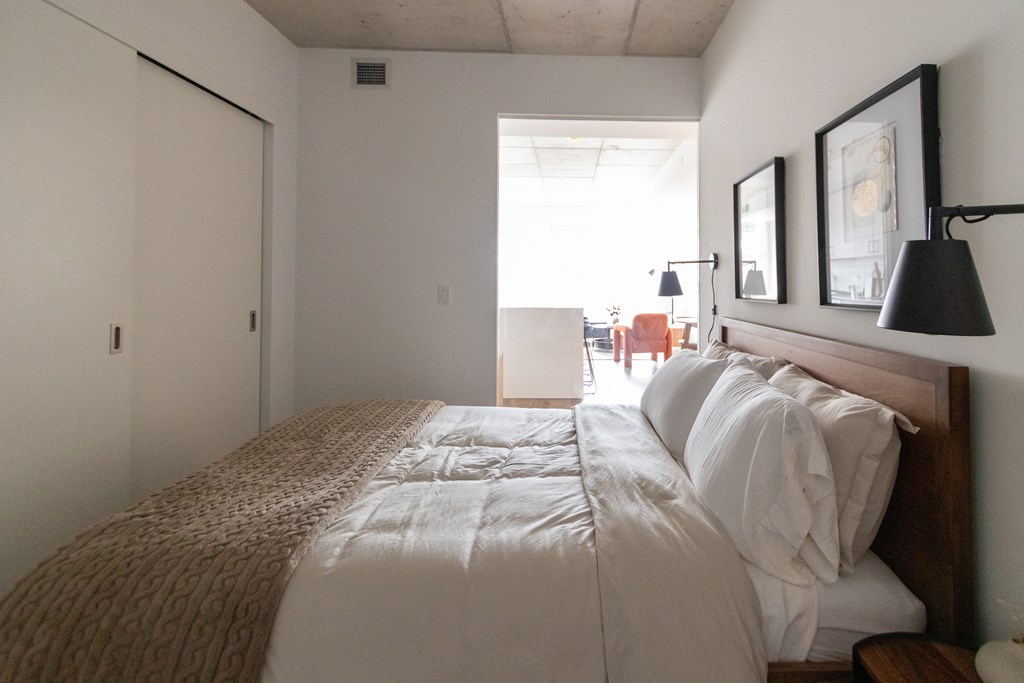 a bedroom with a bed and a door to a living room