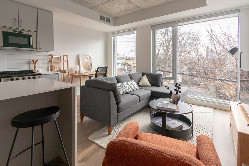 a living room with a couch and a kitchen with a large window