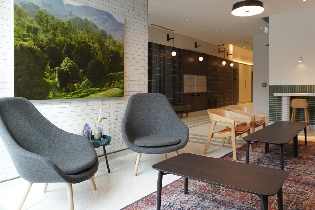 a living room with chairs and tables and a painting on the wall