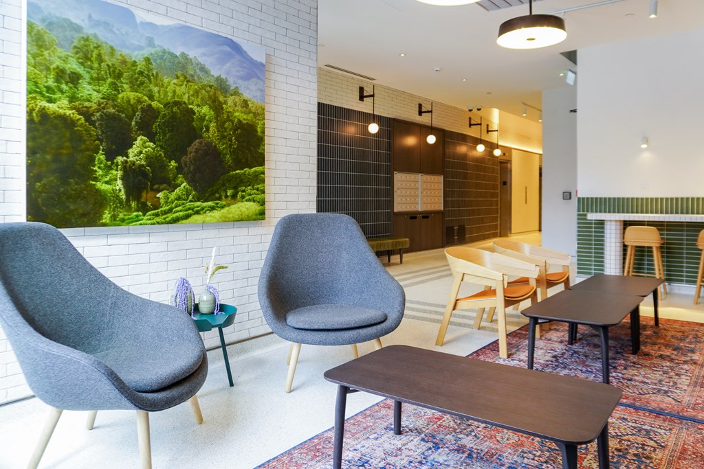 a lounge area with chairs and tables and a large picture of a forest