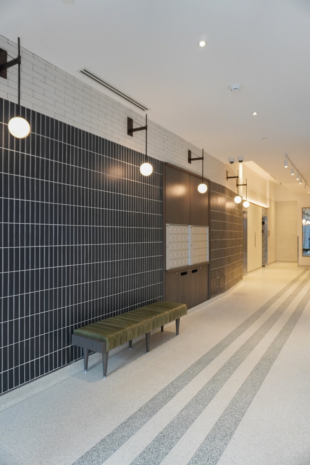 a long hallway with a bench and lights on the wall