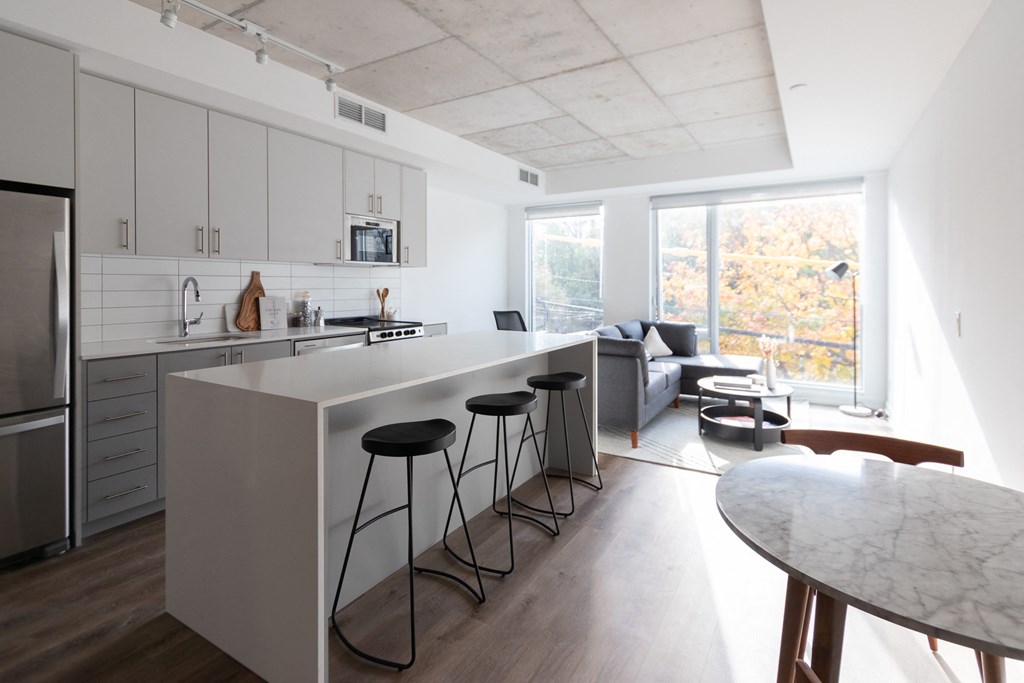 a kitchen with a long island and three stools in front of a white counter