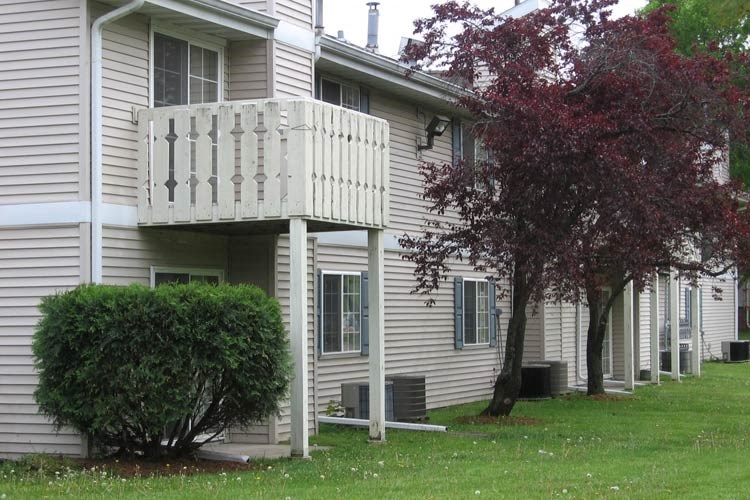 a white house with a balcony and a tree