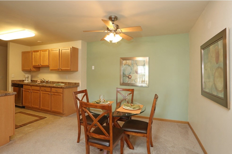 a dining room and kitchen with a ceiling fan and a table and chairs