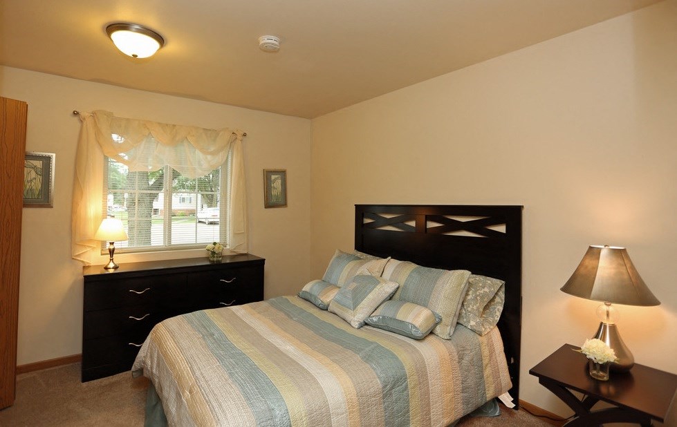 a bedroom with a bed and a dresser and a window