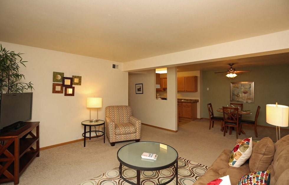 a living room with a couch table and chair and a kitchen in the background