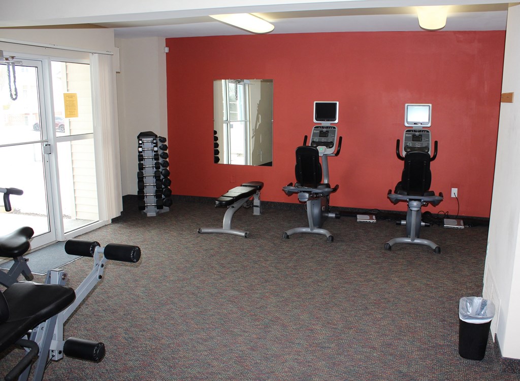 a group of exercise machines in a room with a red wall