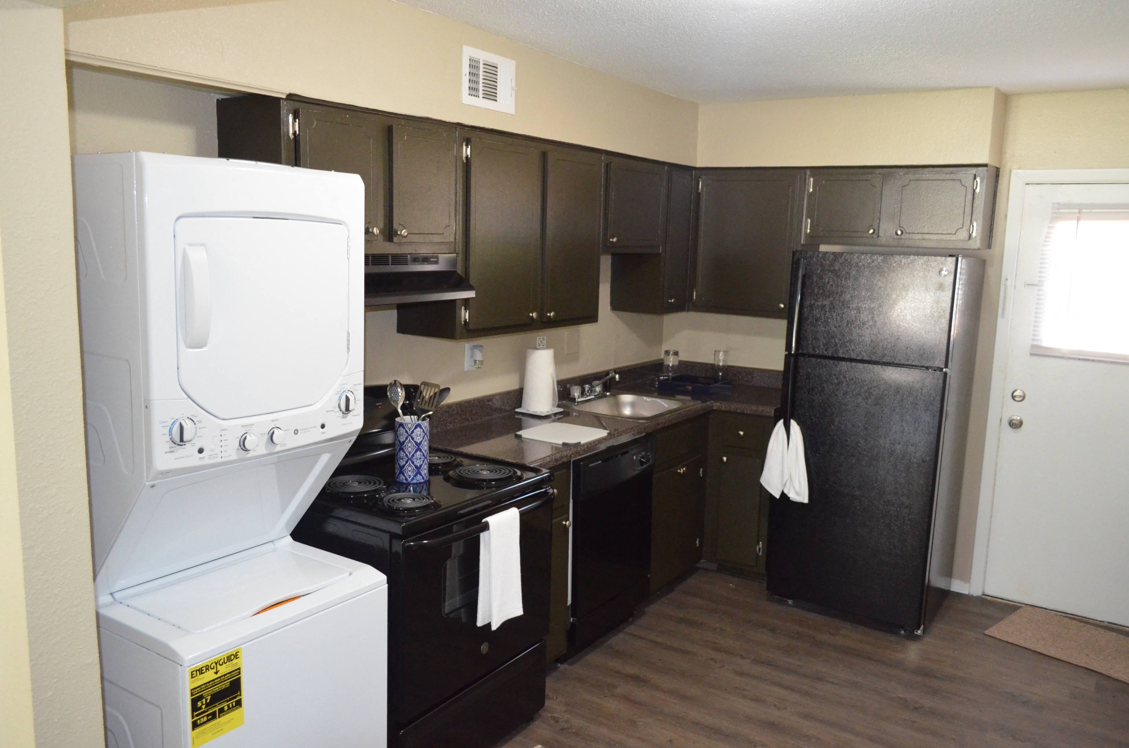a kitchen with black cabinets and a white washer and dryer