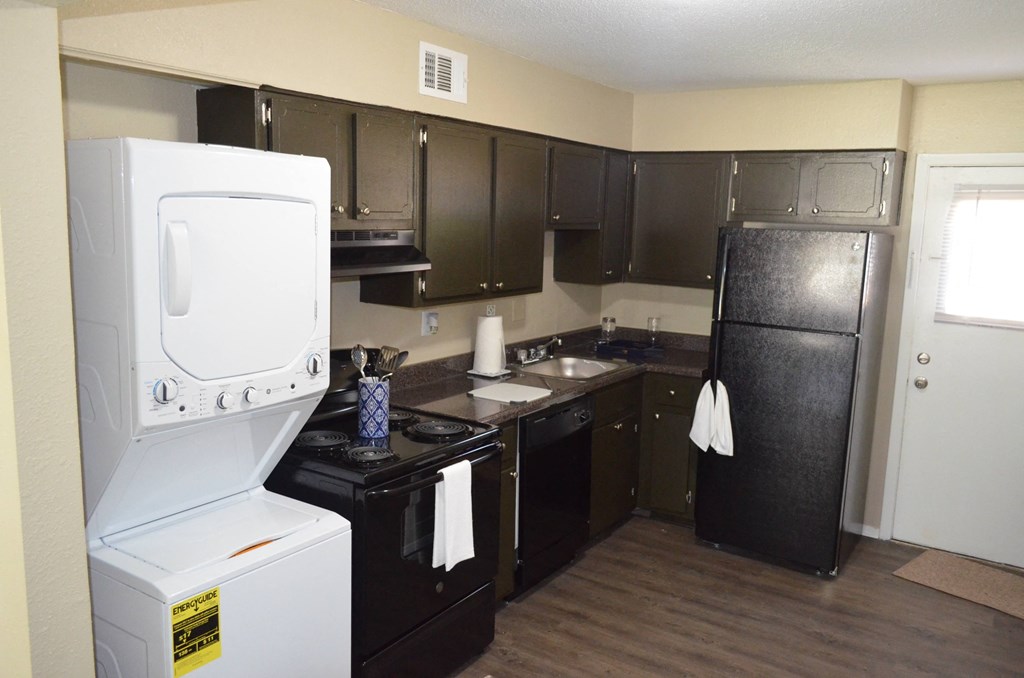 a kitchen with black cabinets and a white washer and dryer