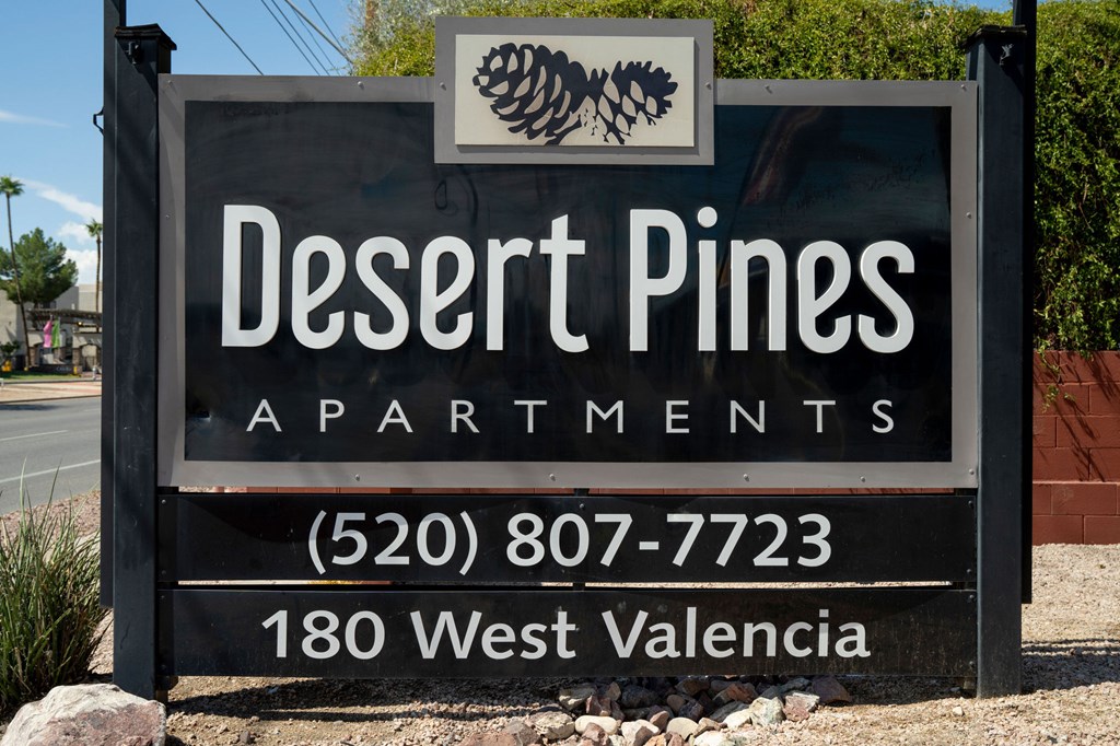 A sign for Desert Pines Apartments with a phone number and address.