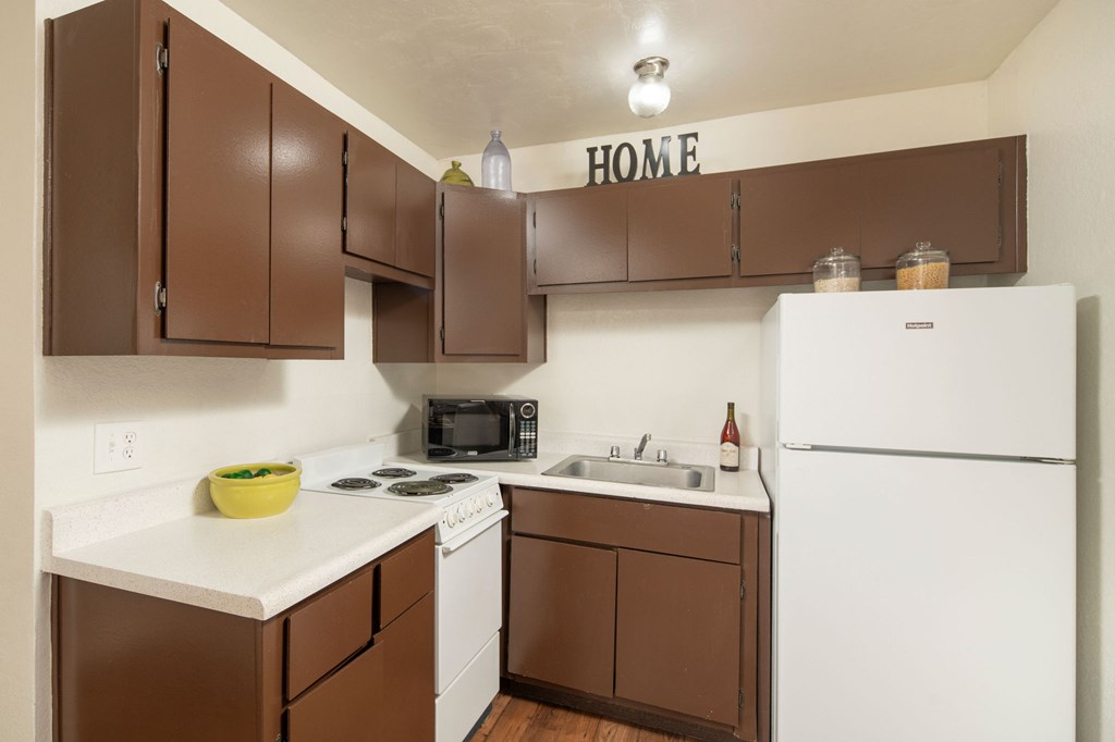 A kitchen with brown cabinets and white appliances.