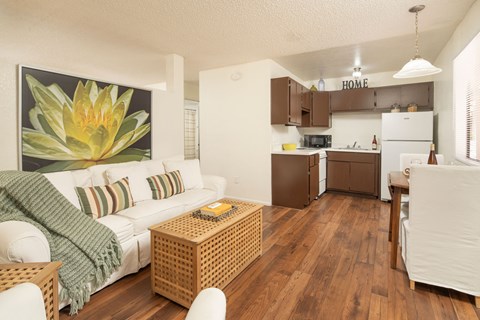 A living room with a white couch and a painting of a yellow flower on the wall.