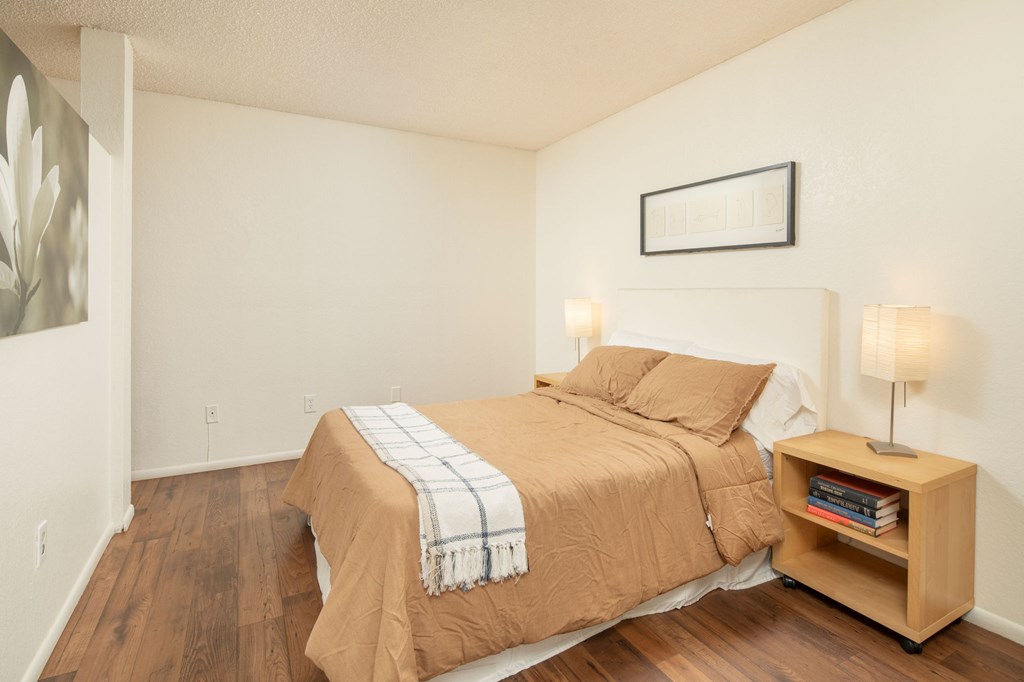 A bedroom with a bed, nightstand, and lamp.