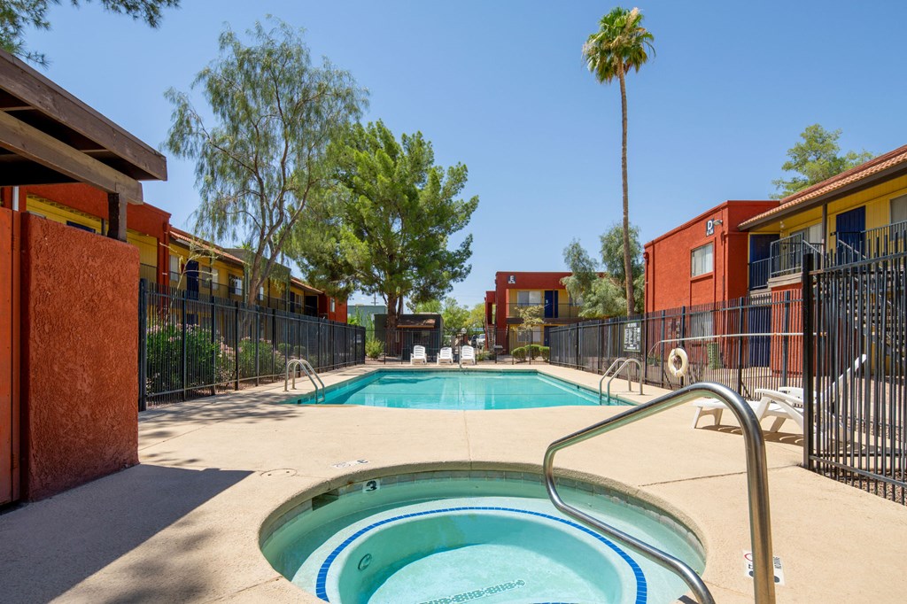 A pool surrounded by red buildings and trees.