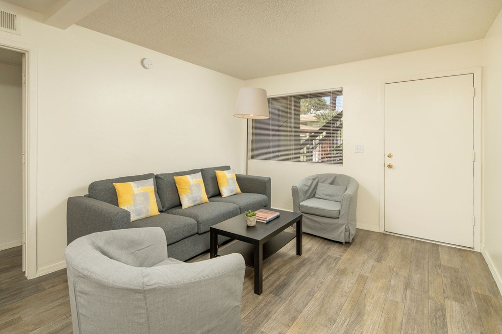 A living room with a grey couch, a grey armchair, and a black coffee table.