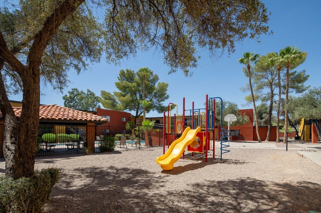 A playground with a yellow slide and red and blue swings.
