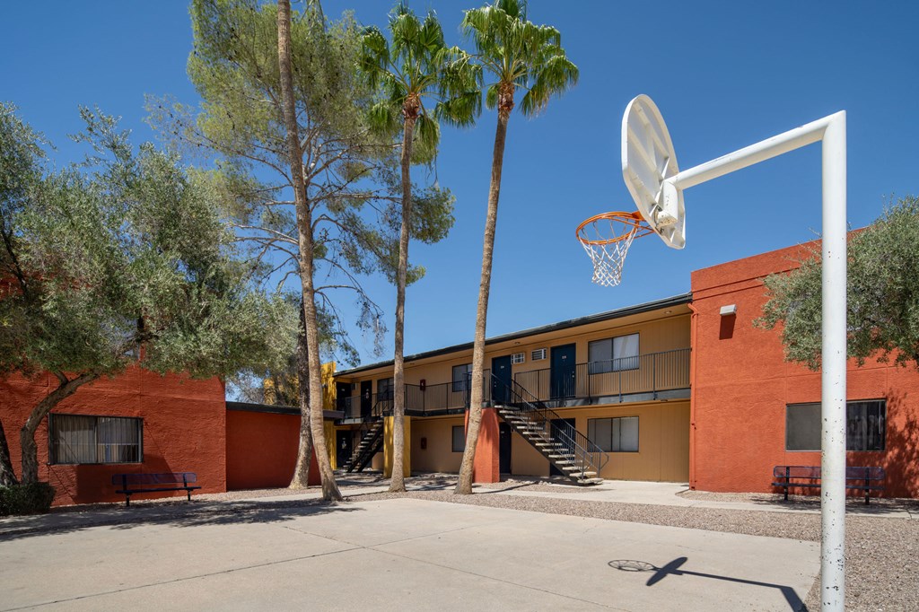 A basketball court with a hoop and a building in the background.