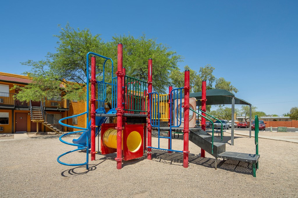 A playground with a red and blue slide and a yellow and red tunnel.