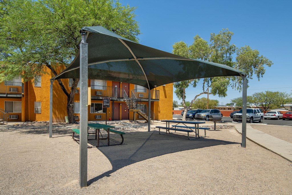 A playground with a green canopy and a picnic table.
