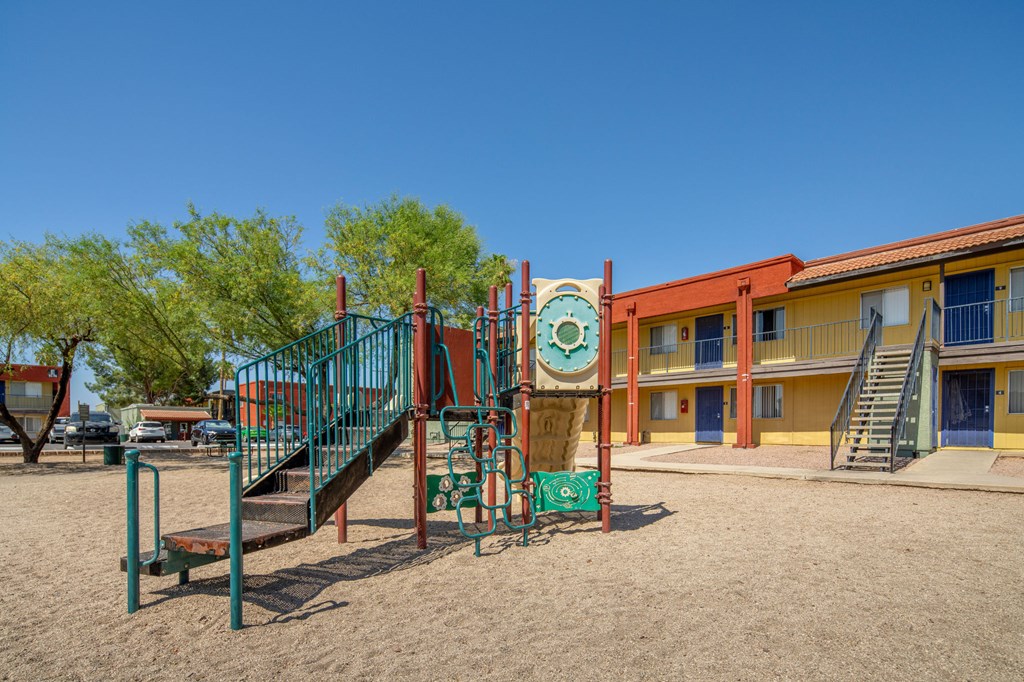 A playground with a slide and a green tree.