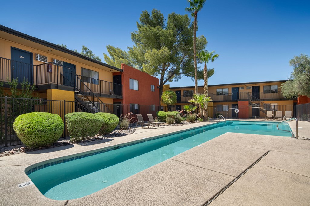 A swimming pool in front of a building with a tree in the background.