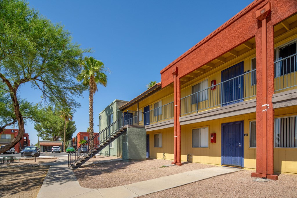 A building with a red and yellow facade has a blue door and a balcony.