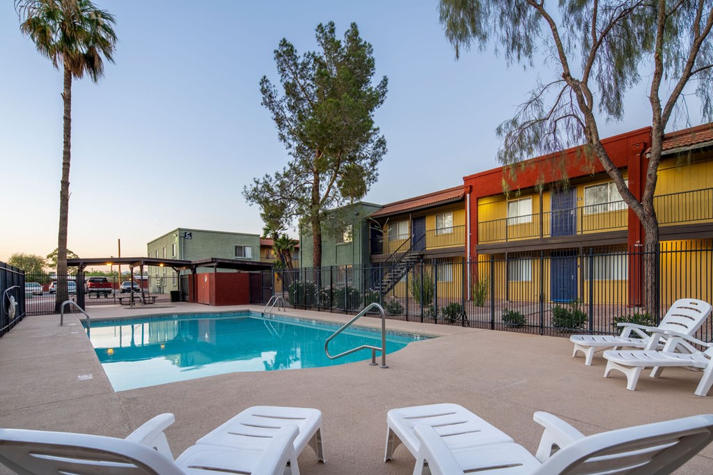 A pool surrounded by lounge chairs and trees.