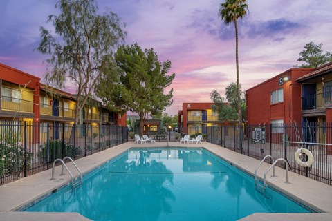 A swimming pool surrounded by a fence and buildings.
