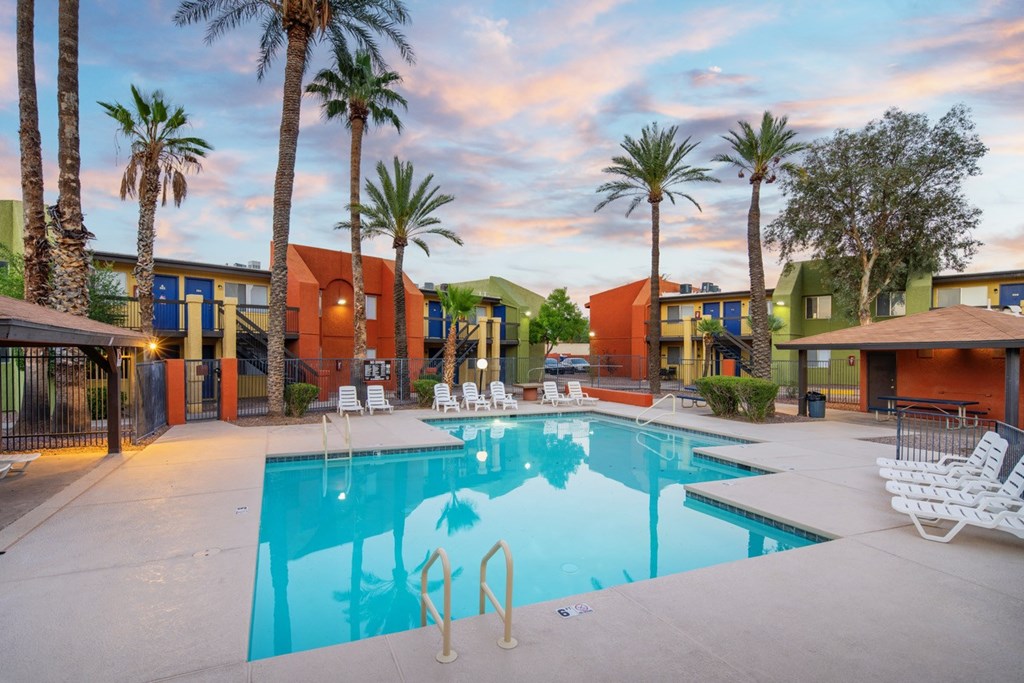 A swimming pool surrounded by palm trees and lounge chairs.