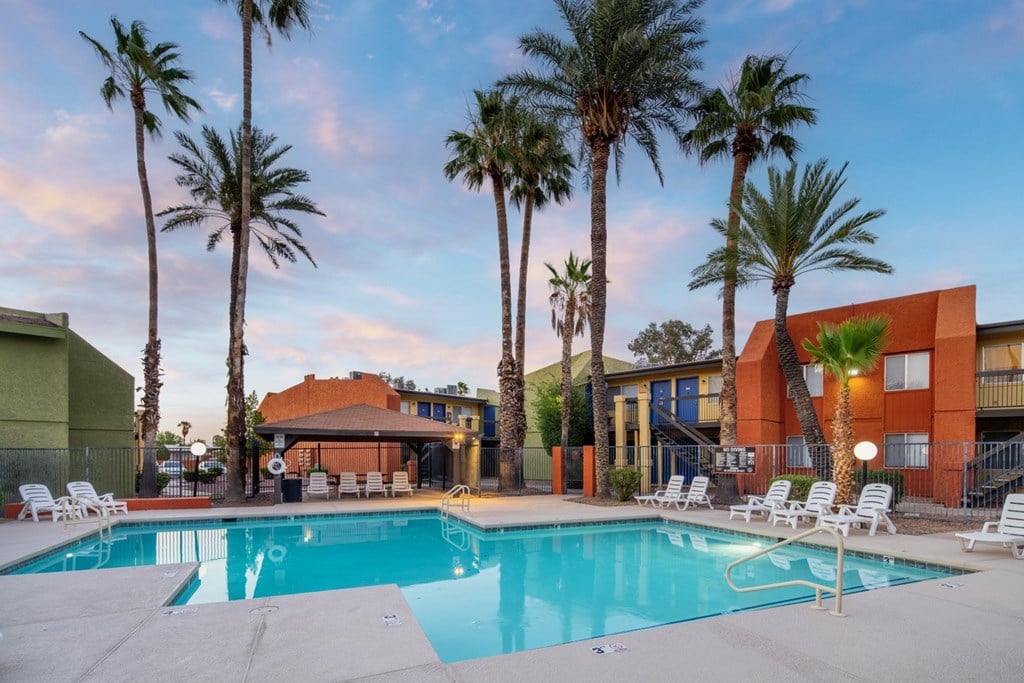 A swimming pool surrounded by palm trees and lounge chairs.