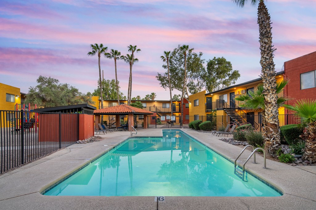 A swimming pool in a resort with a sunset in the background.