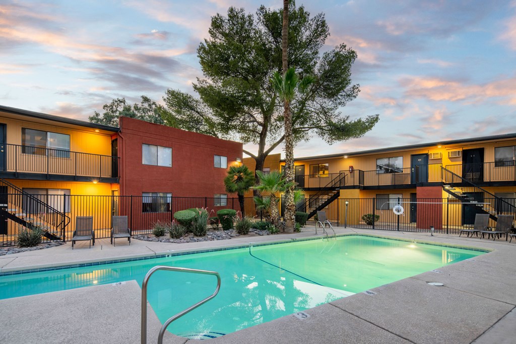 A swimming pool in front of a building with a tree in the background.