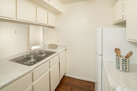 A kitchen with white cabinets and a white fridge.