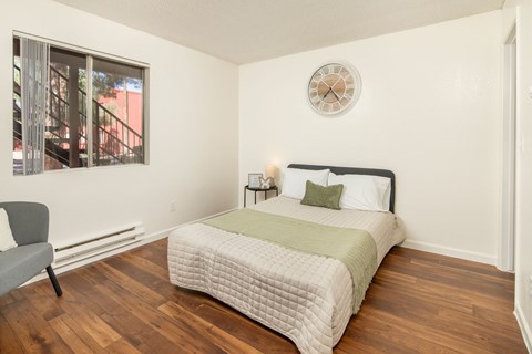 A bedroom with a bed, chair, and window.