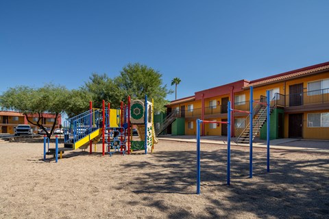 A playground with a slide and swings in front of a building.