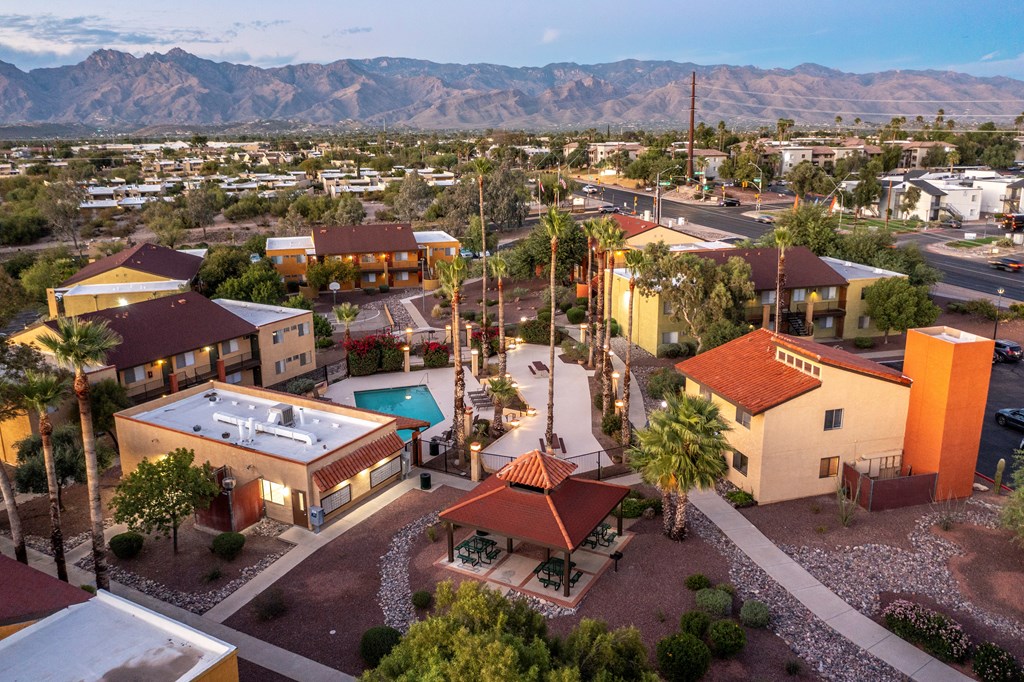 A sunset view of a neighborhood with a pool and a mountain in the background.