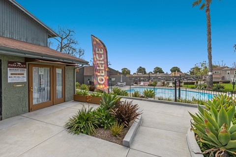 The image shows a building with a sign that reads "PARK PLAZA" and a pool area with a red banner.