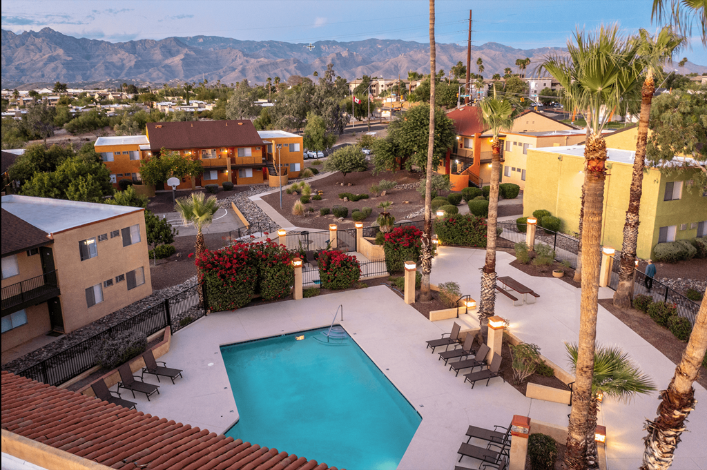 A pool surrounded by palm trees and a mountain range in the background.