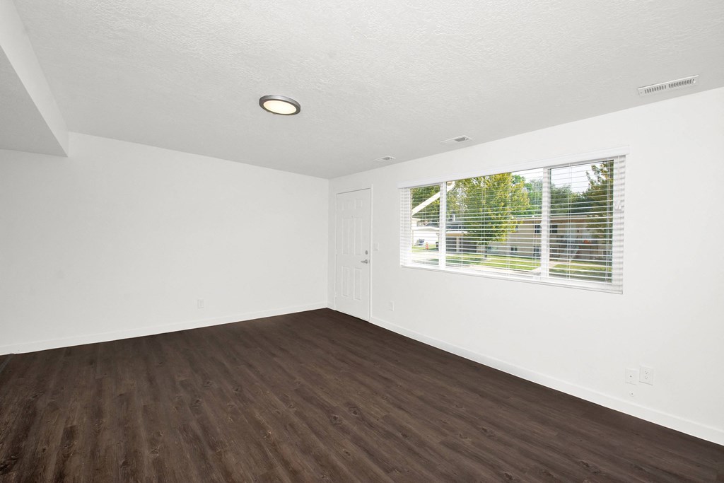 an empty living room with wood floors and a window