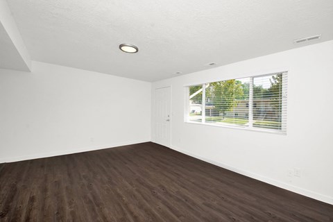 an empty living room with wood floors and a window