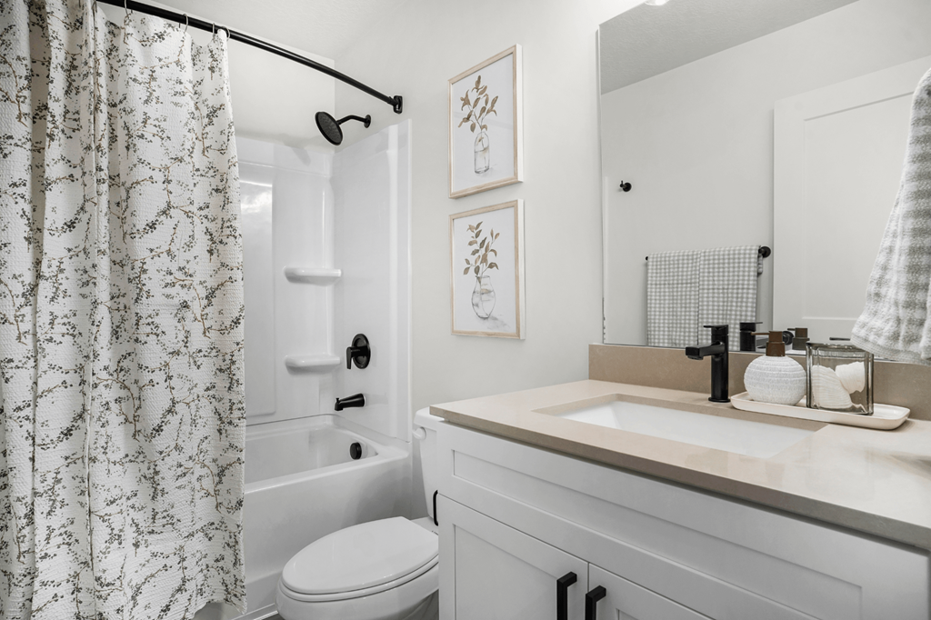 A white bathroom with a toilet, sink, and shower.