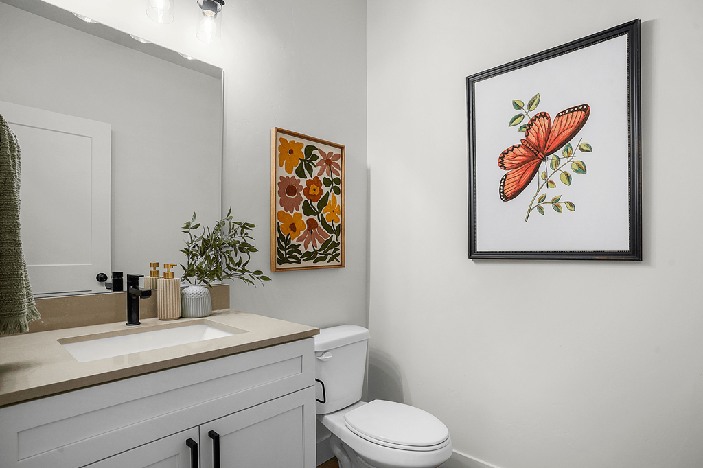 A bathroom with a toilet, sink, and a picture of a butterfly on the wall.