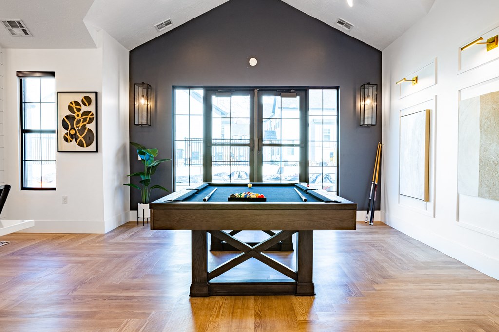 a pool table in a living room with windows