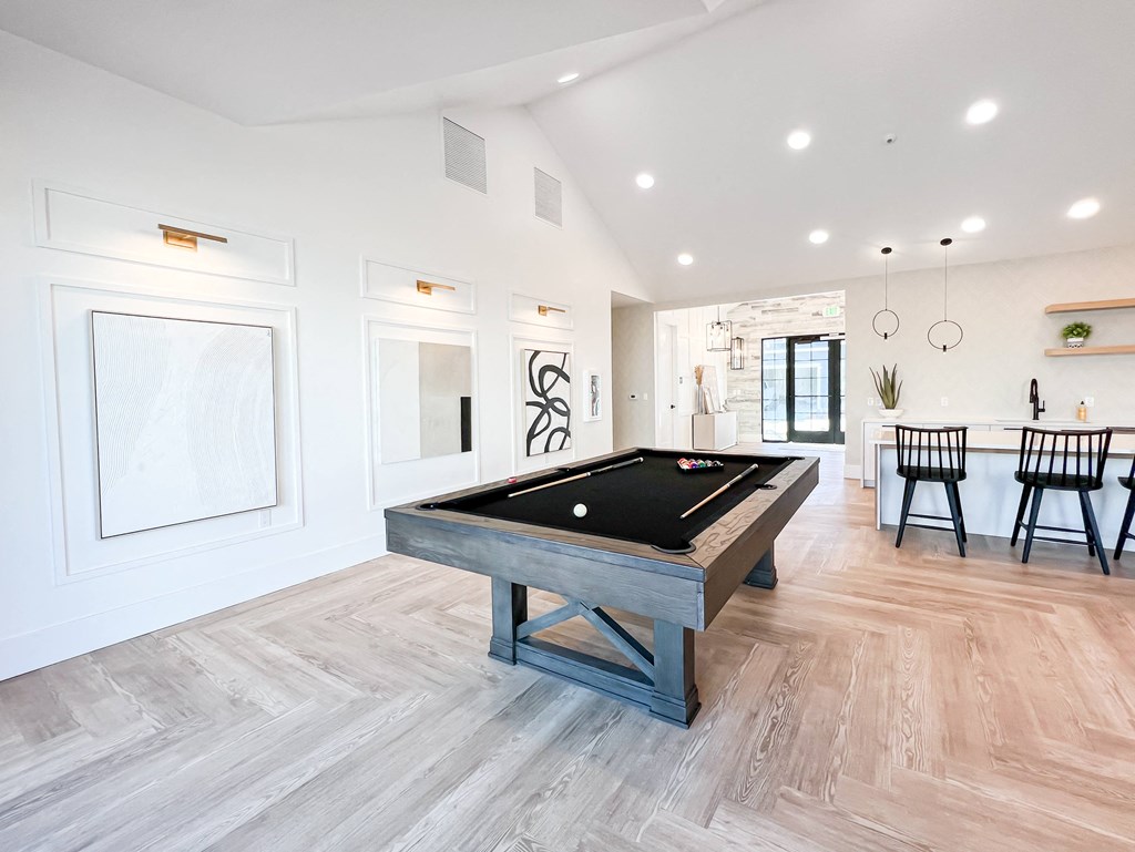 a billiards table in a game room with a dining area and a kitchen