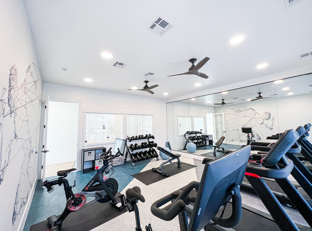 a gym with treadmills and other exercise equipment in a room with windows